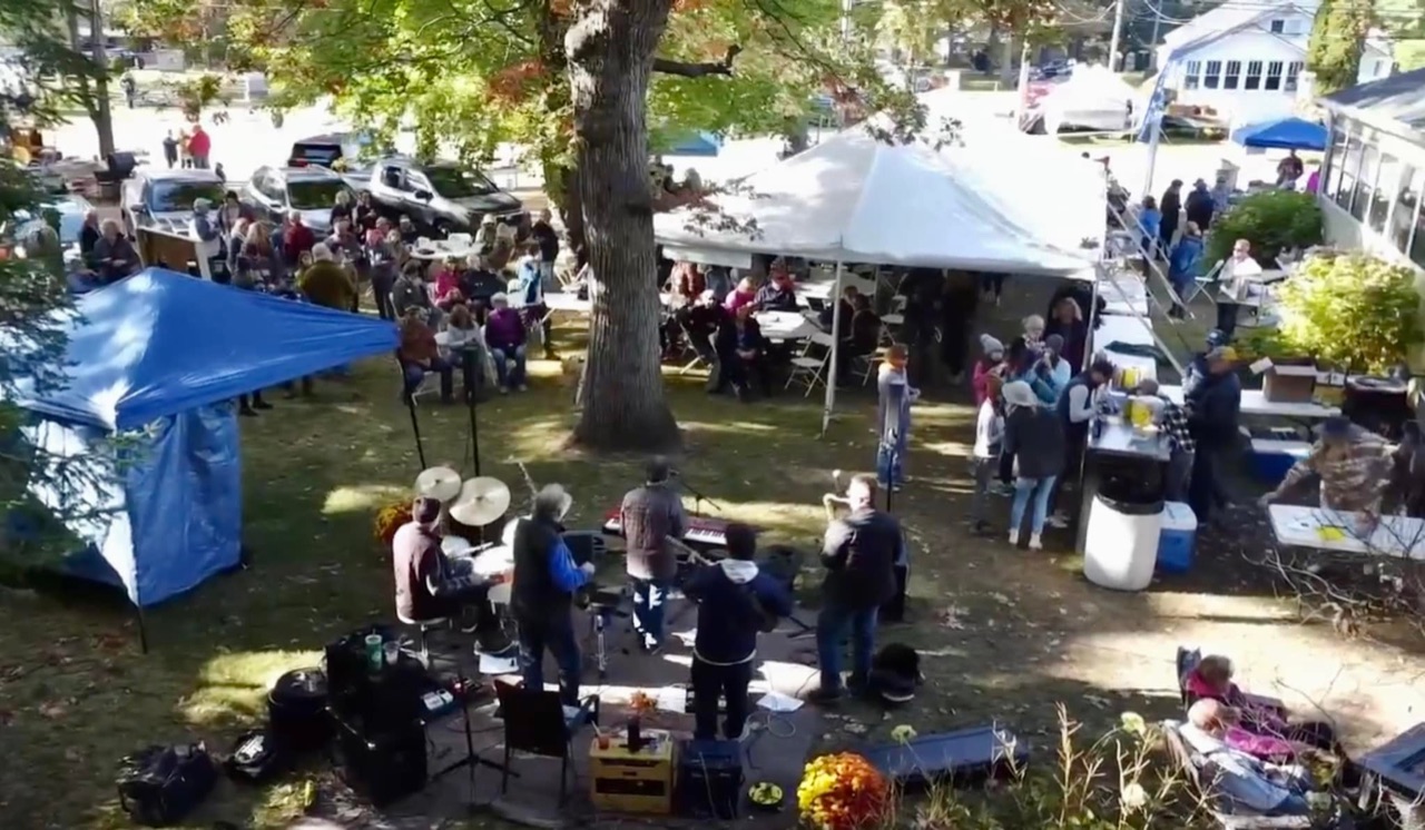 A live band playing to a seated crowd under the tents at 715 Harvest Fest